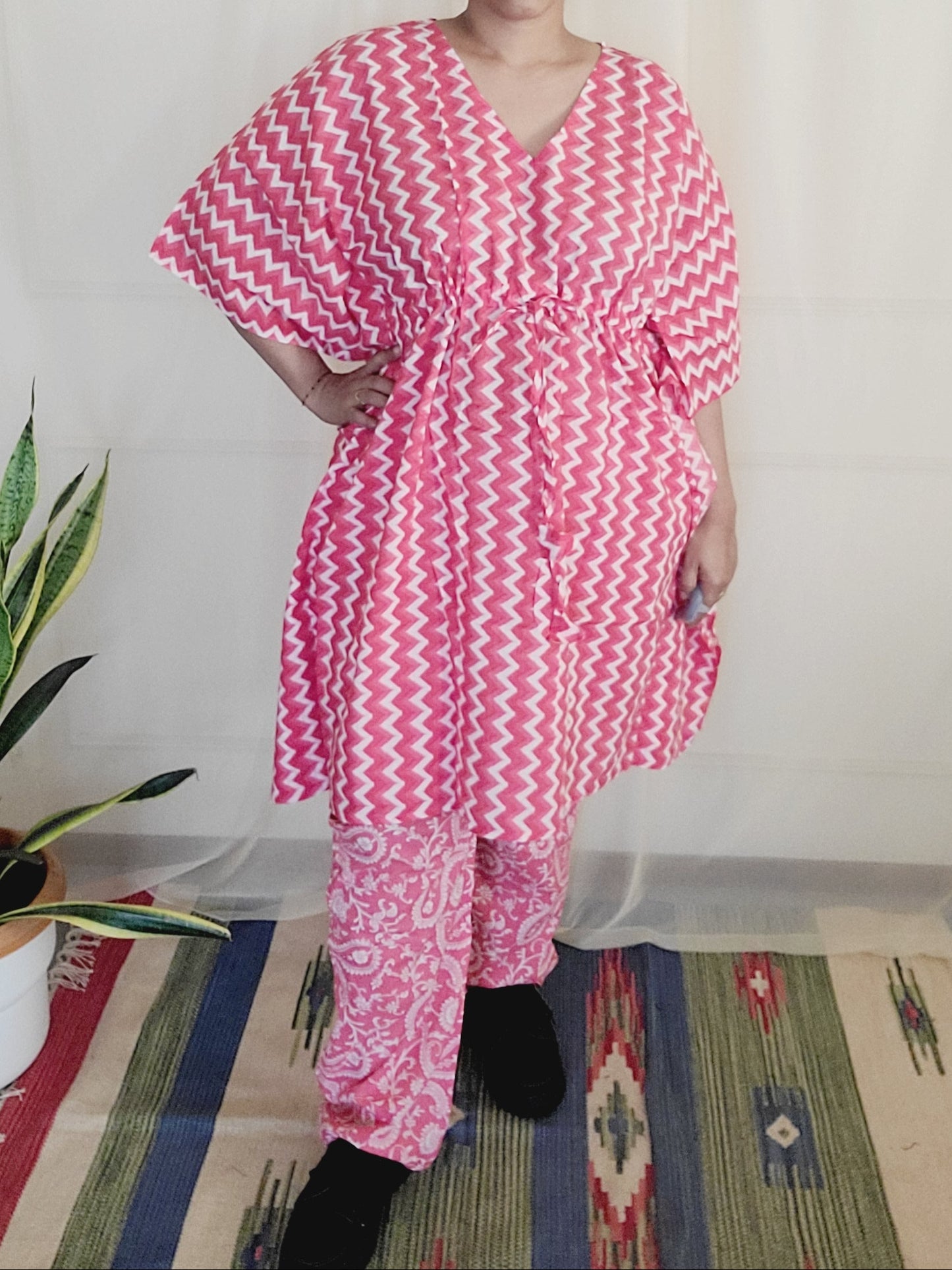 Person wearing a pink and white striped dress lying on a couch with a plant in the background