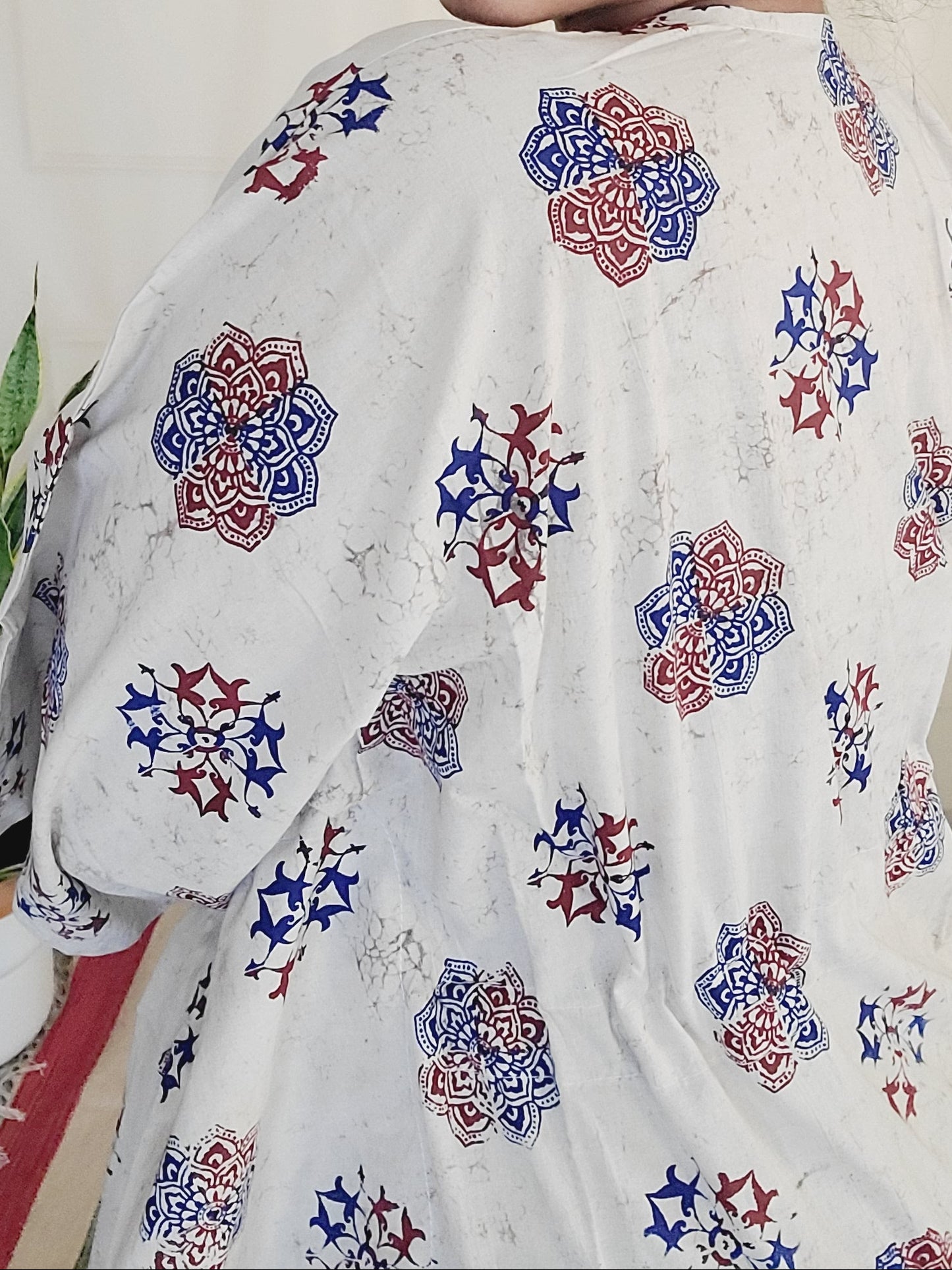 Person wearing a white embroidered shirt with colorful patterns, lying on a light-colored surface.